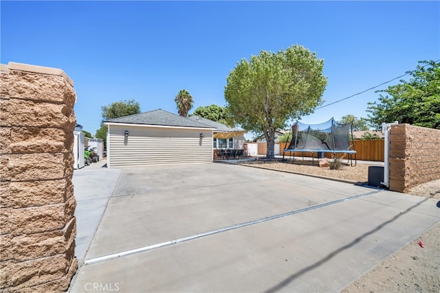 exterior space featuring a garage, a trampoline, and an outbuilding