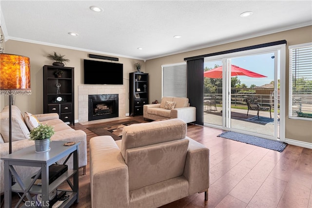 living room with ornamental molding, a textured ceiling, a fireplace, and hardwood / wood-style floors