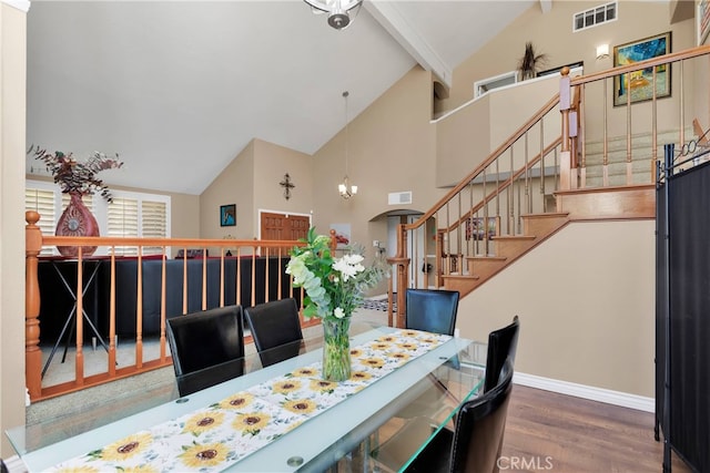 dining area with wood-type flooring, an inviting chandelier, and high vaulted ceiling