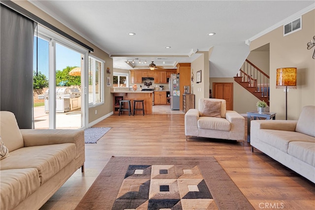 living room with ornamental molding and light hardwood / wood-style floors