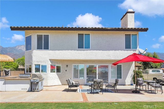 back of house featuring a mountain view and a patio area