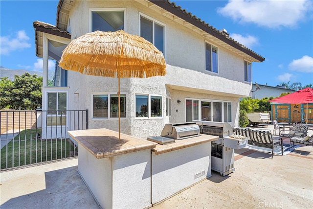 rear view of property featuring an outdoor kitchen and a patio area