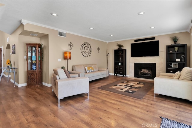 living room featuring a fireplace, crown molding, and hardwood / wood-style floors