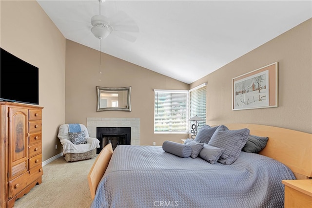 bedroom with lofted ceiling, a tiled fireplace, ceiling fan, and light colored carpet