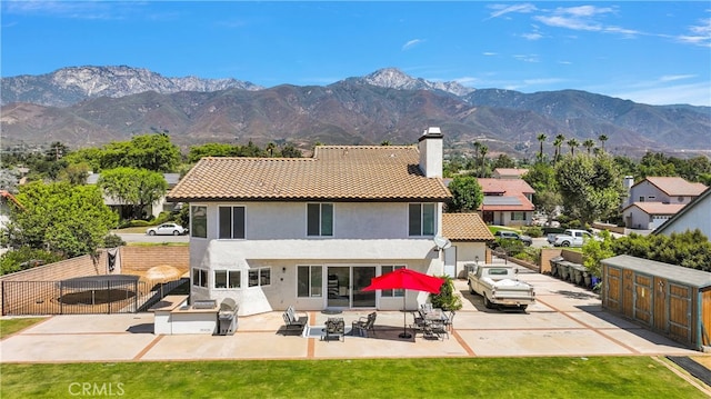 back of property with a mountain view, a yard, and a patio