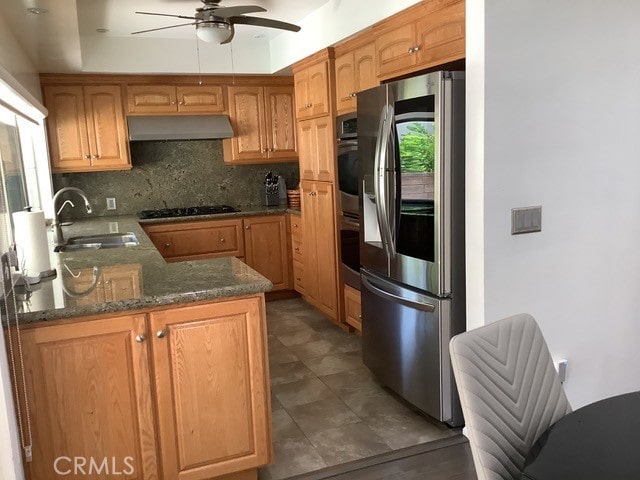 kitchen featuring appliances with stainless steel finishes, decorative backsplash, kitchen peninsula, ceiling fan, and sink