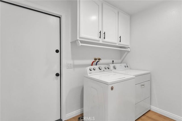 clothes washing area featuring light hardwood / wood-style floors, cabinets, and independent washer and dryer