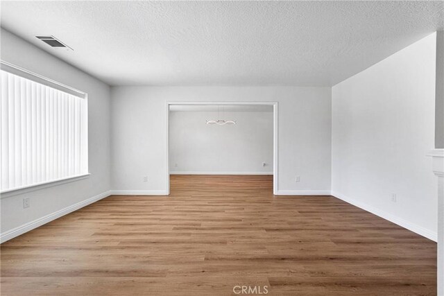 spare room featuring a textured ceiling and light hardwood / wood-style flooring