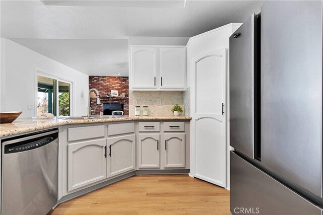 kitchen featuring sink, stainless steel appliances, light stone counters, white cabinets, and light wood-type flooring