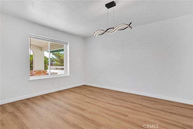 unfurnished dining area featuring a textured ceiling and light wood-type flooring