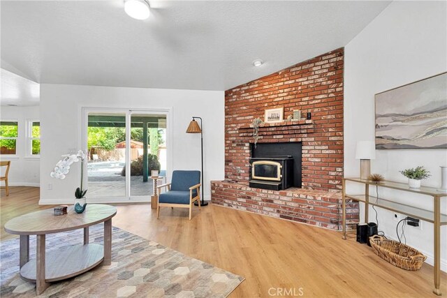 living room featuring a wood stove, hardwood / wood-style floors, and lofted ceiling