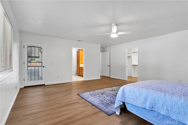 bedroom featuring ceiling fan, ensuite bathroom, wood-type flooring, and a spacious closet