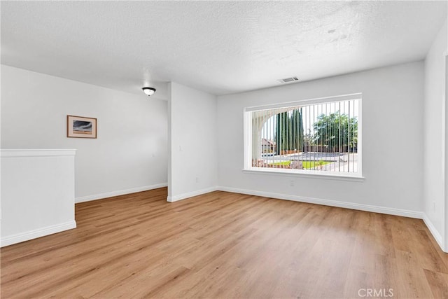 spare room featuring a textured ceiling and light wood-type flooring