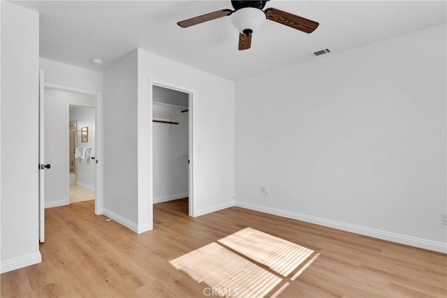 unfurnished bedroom with ceiling fan, light hardwood / wood-style floors, a spacious closet, and a closet