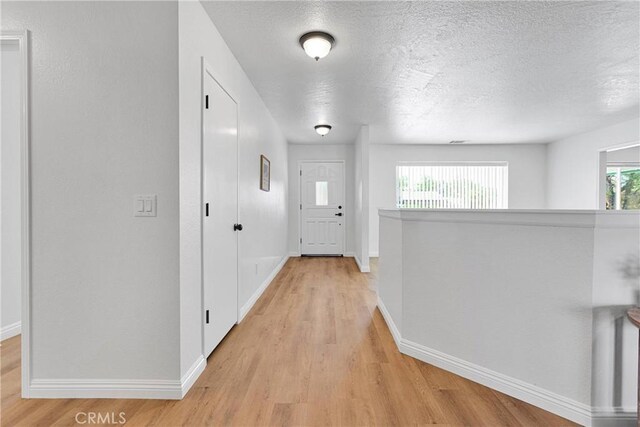 hallway featuring light hardwood / wood-style flooring and a textured ceiling