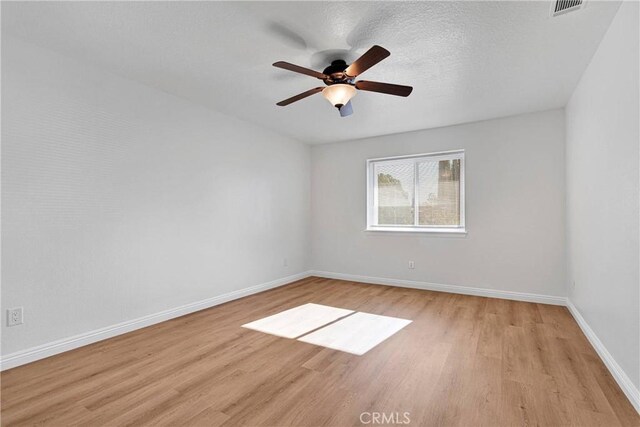 empty room featuring ceiling fan, light hardwood / wood-style floors, and a textured ceiling