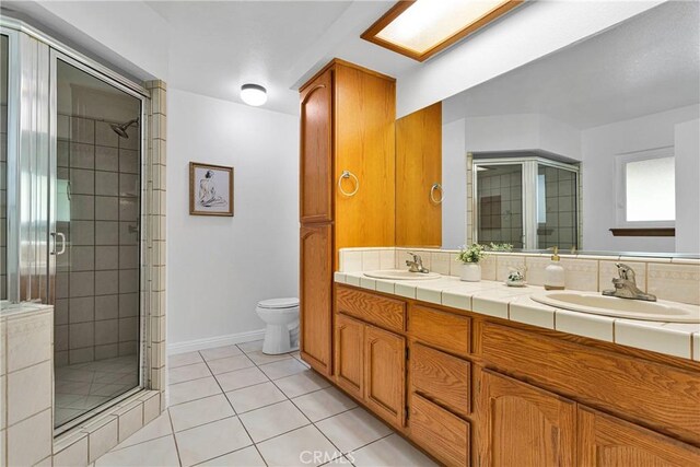 bathroom featuring toilet, vanity, tile patterned floors, and walk in shower