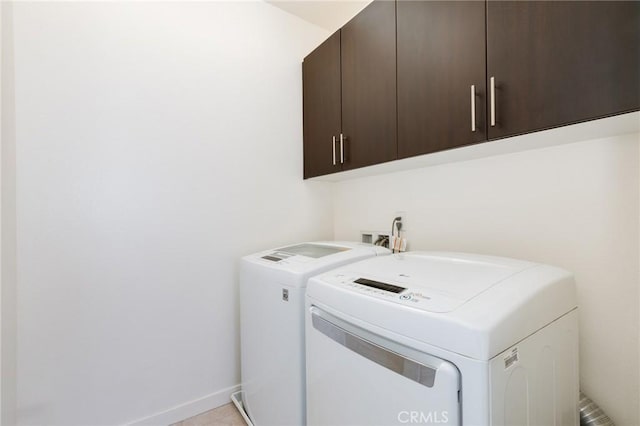 clothes washing area featuring light tile patterned floors, cabinets, and independent washer and dryer