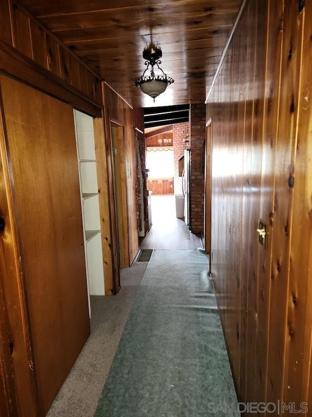 hall with carpet, wood ceiling, and wood walls