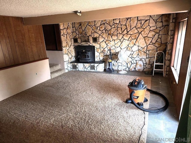 unfurnished living room featuring beam ceiling, plenty of natural light, wood walls, and a textured ceiling