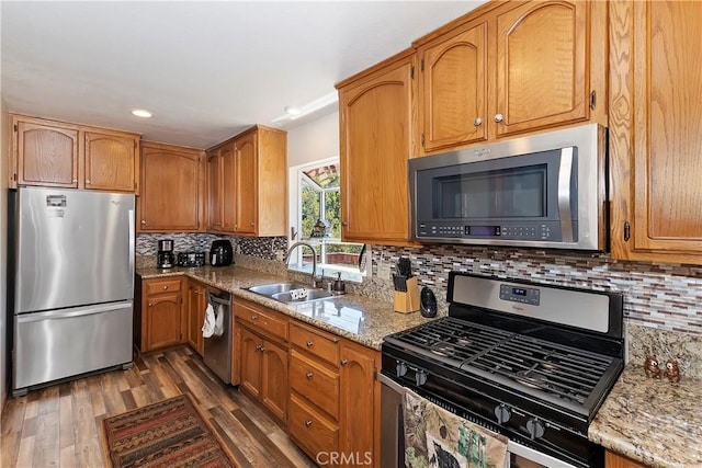 kitchen with light stone countertops, tasteful backsplash, stainless steel appliances, dark wood-type flooring, and sink