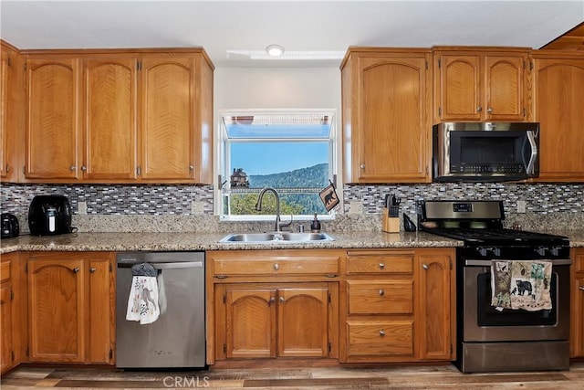 kitchen with decorative backsplash, light wood-type flooring, stainless steel appliances, and sink