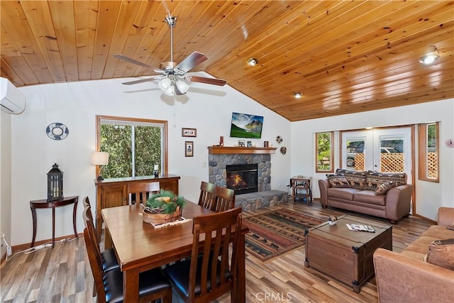 dining room with light hardwood / wood-style floors, a stone fireplace, lofted ceiling, and wood ceiling