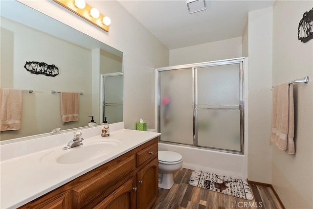 full bathroom featuring wood-type flooring, vanity, toilet, and enclosed tub / shower combo