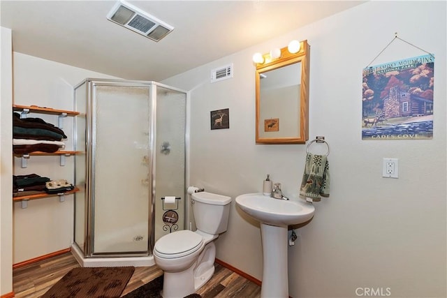 bathroom featuring wood-type flooring, toilet, and an enclosed shower