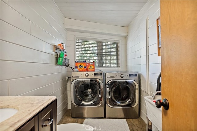 clothes washing area with washer and clothes dryer, dark hardwood / wood-style floors, and wood walls