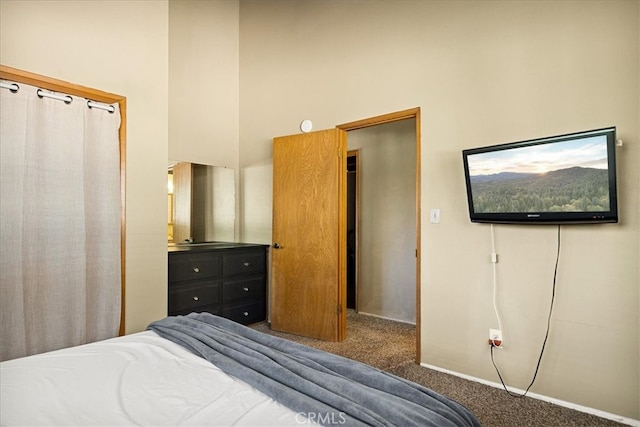 bedroom with a closet, a towering ceiling, and dark colored carpet