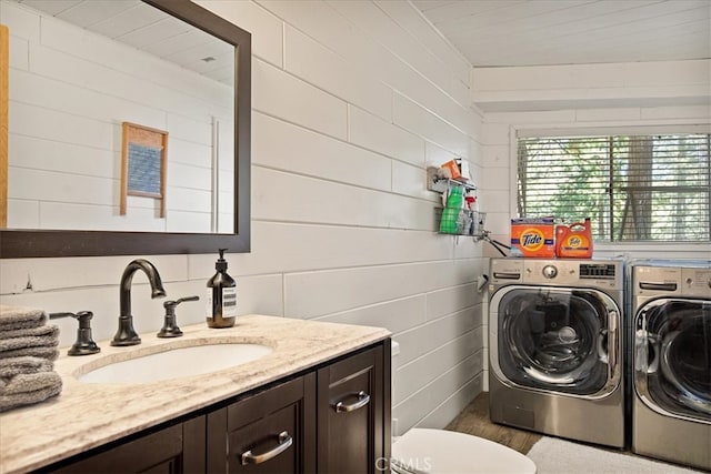 clothes washing area with washer and dryer, sink, and dark hardwood / wood-style flooring