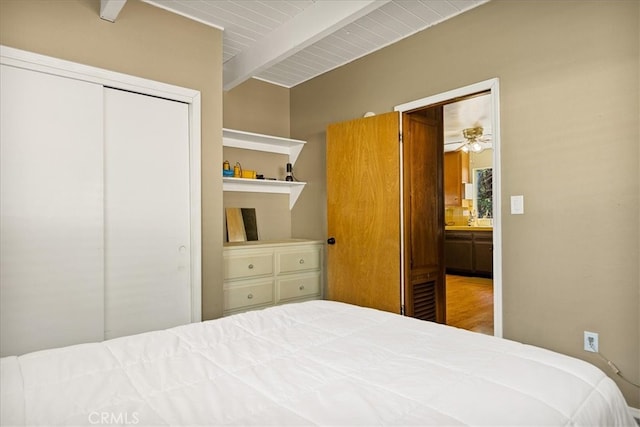 bedroom featuring a closet, beam ceiling, hardwood / wood-style flooring, and wooden ceiling