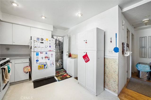 kitchen featuring white cabinets, white appliances, washer / clothes dryer, and light wood-type flooring