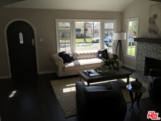 living room featuring vaulted ceiling, a fireplace, and dark hardwood / wood-style flooring