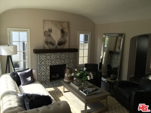 living room with lofted ceiling and a tiled fireplace