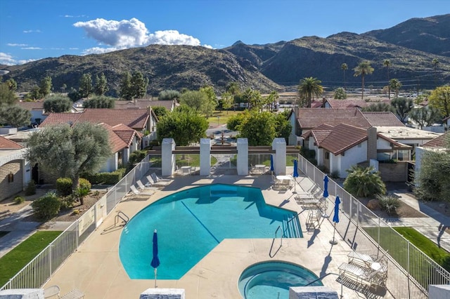 view of pool featuring a mountain view, a patio, and a hot tub