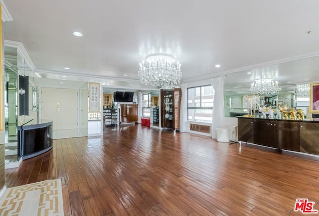 unfurnished living room with wood-type flooring, crown molding, and an inviting chandelier