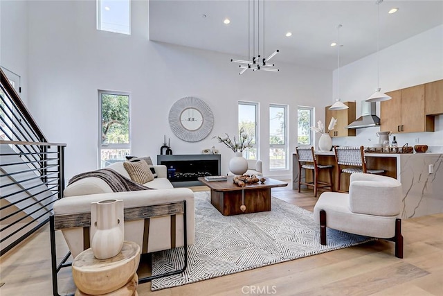 living room with plenty of natural light, a towering ceiling, and light hardwood / wood-style floors