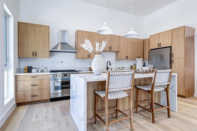 2304 Grant Ave Unit A, Redondo Beach, CA 90278 - kitchen featuring appliances with stainless steel finishes, wall chimney range hood, light wood finished floors, a kitchen breakfast bar, and a towering ceiling