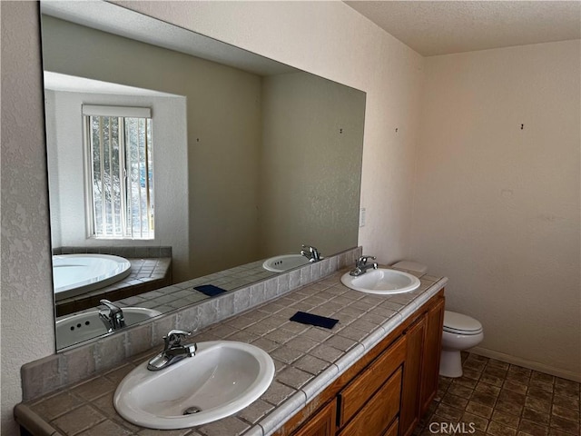 bathroom featuring vanity, a bathtub, toilet, and a textured ceiling