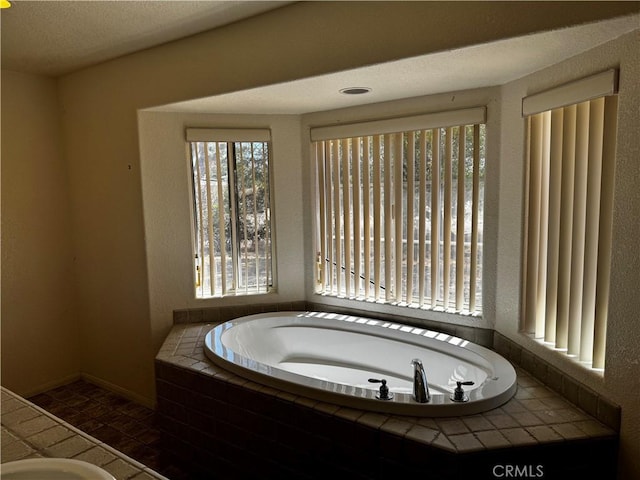 bathroom featuring tile patterned flooring, a textured ceiling, and tiled tub