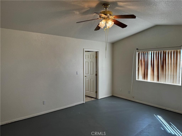 unfurnished room with ceiling fan, concrete flooring, a textured ceiling, and vaulted ceiling