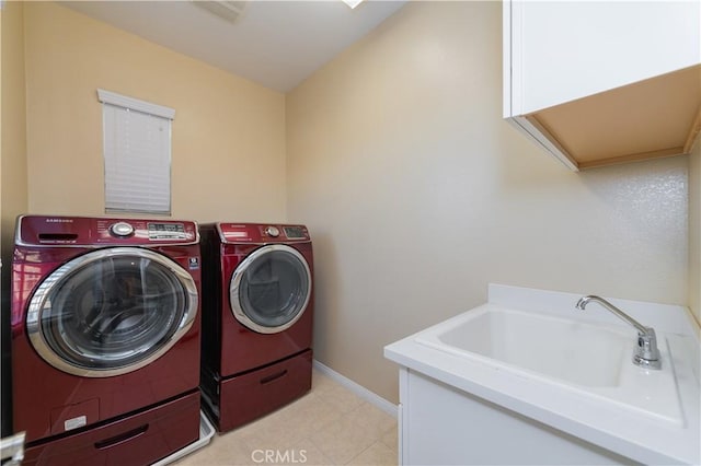 clothes washing area featuring cabinets, washing machine and clothes dryer, and sink