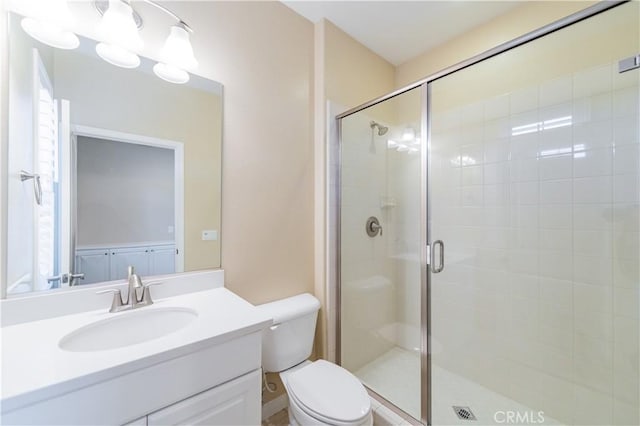 bathroom featuring vanity, a shower with door, and toilet