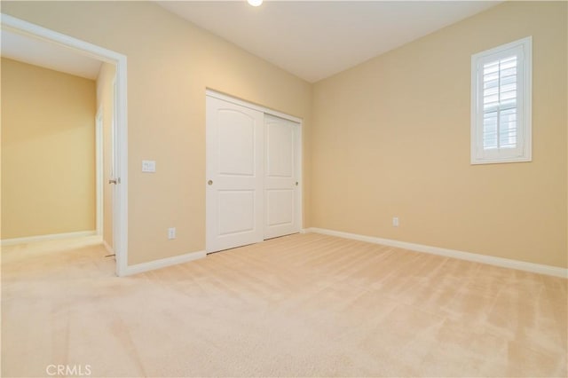 unfurnished bedroom with light colored carpet and a closet