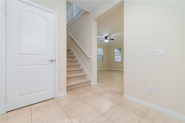 stairway with ceiling fan, ornamental molding, and tile patterned flooring