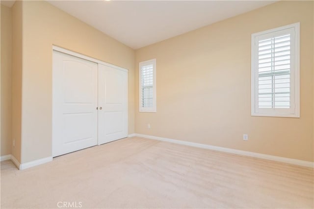 unfurnished bedroom with light carpet and a closet