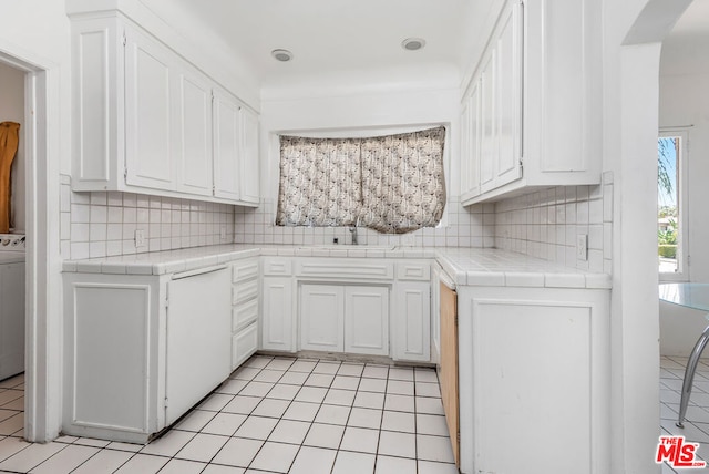 kitchen with white cabinets, backsplash, light tile patterned floors, tile countertops, and sink