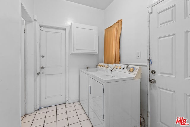 laundry area with washing machine and clothes dryer, light tile patterned floors, and cabinets